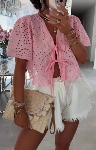Rosa blus i bomull med broderade detaljer och knytband framtill. Kortare modell – modellen bär one size (passar XS–L).