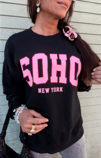 Svart collegetröja med rosa SOHO – New York-tryck, muddar och rund hals, fotad framifrån – i mjuk bomull med avslappnad passform.