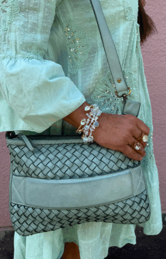 Turkos clutch/axelväska i flätat läder med handrem och justerbar axelrem, handgjord i Italien, fotad framifrån med turkost innerfoder synligt.