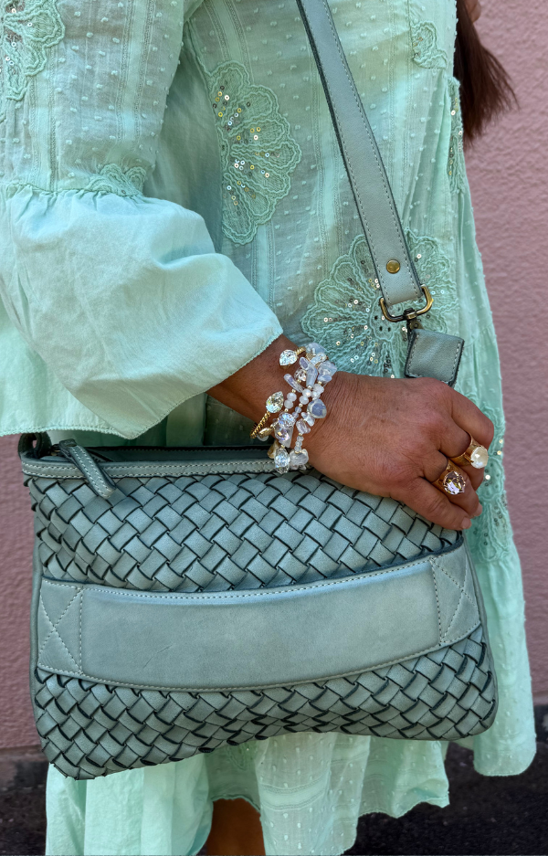 Turkos clutch/axelväska i flätat läder med handrem och justerbar axelrem, handgjord i Italien, fotad framifrån med turkost innerfoder synligt.