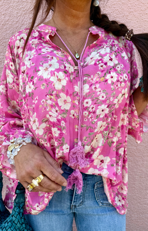 Susanne Blouse i cerise med offwhite blommor, viskosblus med knytband och volangärmar, fotad framifrån på modell med avslappnad stil.