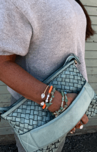 Turkos clutch/axelväska i flätat läder med handrem och justerbar axelrem, handgjord i Italien, fotad framifrån med turkost innerfoder synligt.