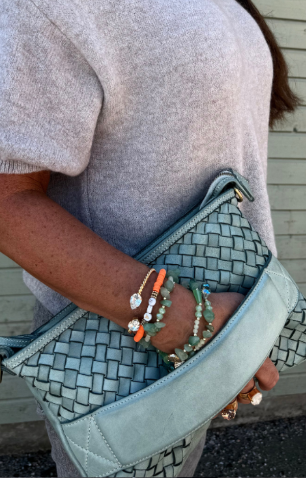 Turkos clutch/axelväska i flätat läder med handrem och justerbar axelrem, handgjord i Italien, fotad framifrån med turkost innerfoder synligt.
