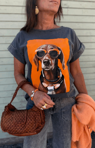 T-shirt med hundmotiv – stilren tecknad hund med stora orangea solglasögon, tryckt på framsidan. Fotad framifrån mot neutral bakgrund.