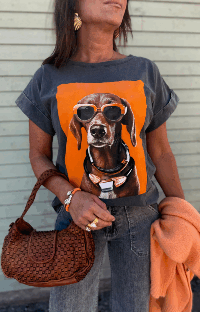 T-shirt med hundmotiv – stilren tecknad hund med stora orangea solglasögon, tryckt på framsidan. Fotad framifrån mot neutral bakgrund.