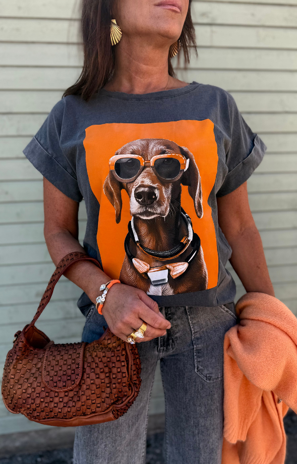 T-shirt med hundmotiv – stilren tecknad hund med stora orangea solglasögon, tryckt på framsidan. Fotad framifrån mot neutral bakgrund.