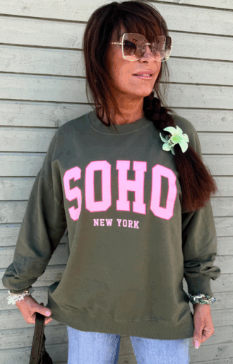 Armygrön collegetröja med rosa SOHO – New York-tryck, mjuk bomull med muddar, fotad framifrån på galge eller modell.