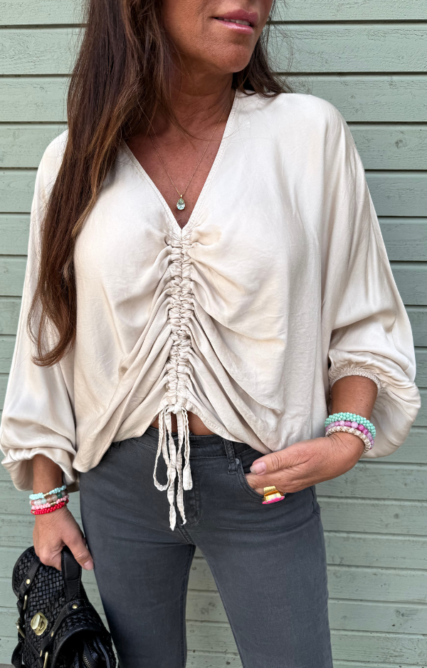 Champagnebeige blus i silkig viskos med trumpetärmar och dragsko framtill – one size, perfekt för vardag eller fest