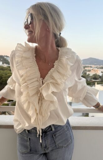 Cremefärgad bomullsblus med volanger, puffärmar och knytband i V-ringning – bohochic stil på modell.