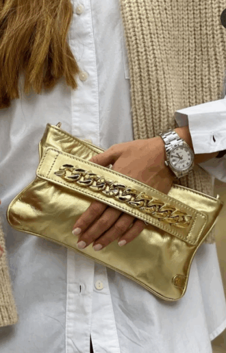 Väska i guldigt läder med dragkedjefack och avtagbar guldaxelrem, 25 cm lång och 15 cm hög.