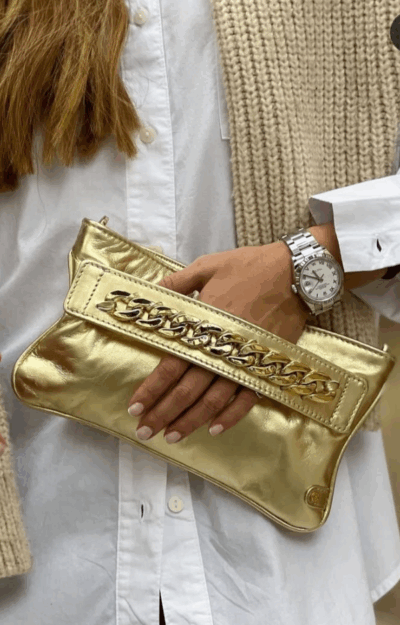 Väska i guldigt läder med dragkedjefack och avtagbar guldaxelrem, 25 cm lång och 15 cm hög.