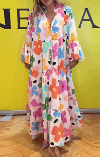 Blommig viskosklänning med färgglada 70-talsblommor, V-ringning med knappar och volanger vid ärmslut.