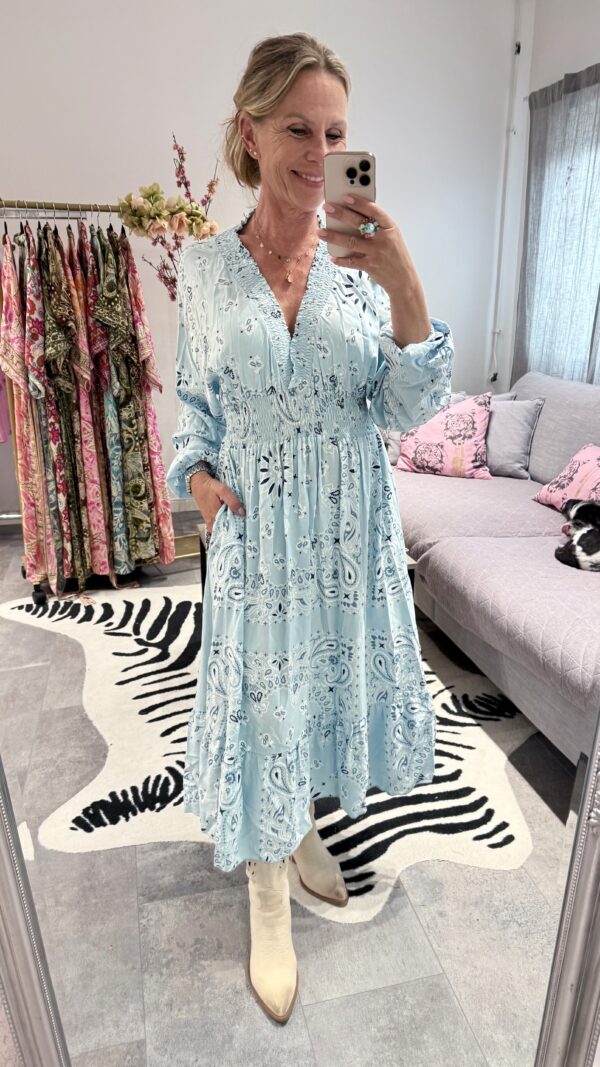 Klänning i viskos med bandanaprint i ljusblå, rosa och coral, med volang och fickor.