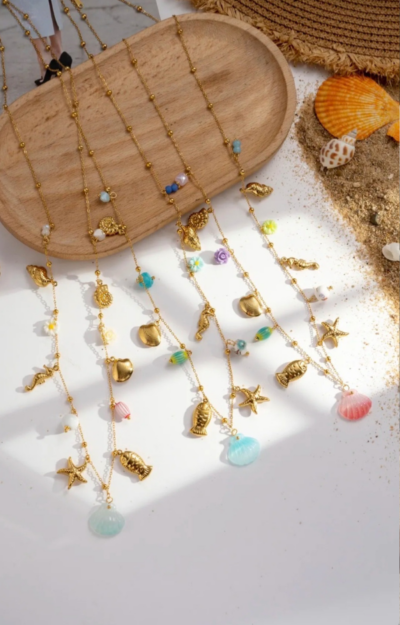Superfint halsband med berlocker i somriga motiv – en lekfull mix av snäckor, sjöhästar, blommor och sjöstjärnor som fångar känslan av sol, strand och semester 🌸🐚 Detta halsband ger direkt liv till din outfit och blir en perfekt detalj för dig som älskar färg, form och boho luxe. Bär det som ett statement-smycke eller kombinera med andra halsband för en mer personlig look. Lika snyggt till klänning som till t-shirt och jeans – ett måste för sommarens alla tillfällen ☀️ 👉 Ett smycke som andas sommar från första sekund.