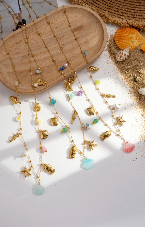 Superfint halsband med berlocker i somriga motiv – en lekfull mix av snäckor, sjöhästar, blommor och sjöstjärnor som fångar känslan av sol, strand och semester 🌸🐚 Detta halsband ger direkt liv till din outfit och blir en perfekt detalj för dig som älskar färg, form och boho luxe. Bär det som ett statement-smycke eller kombinera med andra halsband för en mer personlig look. Lika snyggt till klänning som till t-shirt och jeans – ett måste för sommarens alla tillfällen ☀️ 👉 Ett smycke som andas sommar från första sekund.