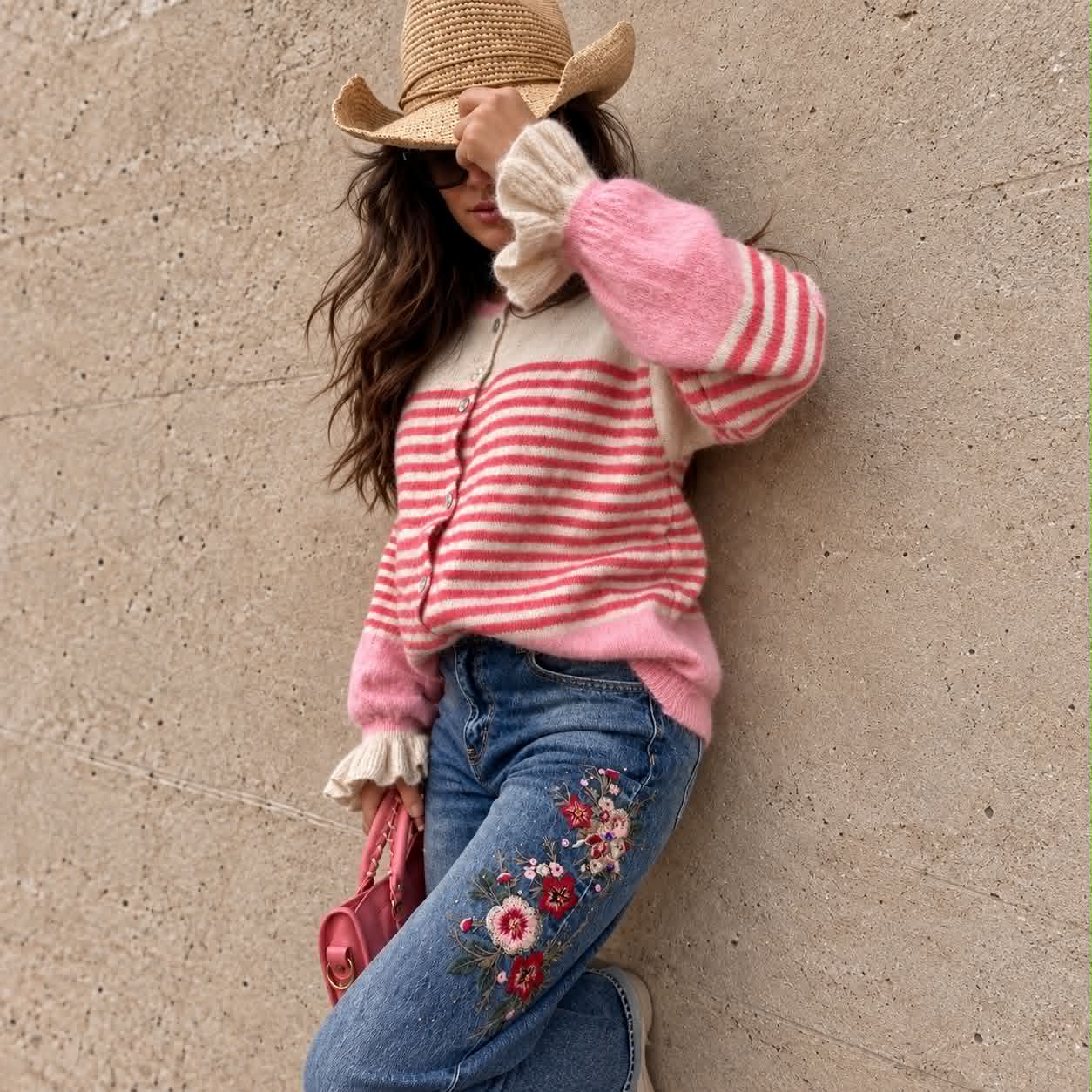Kvinna i randig rosa kofta, halmhatt och broderade jeans